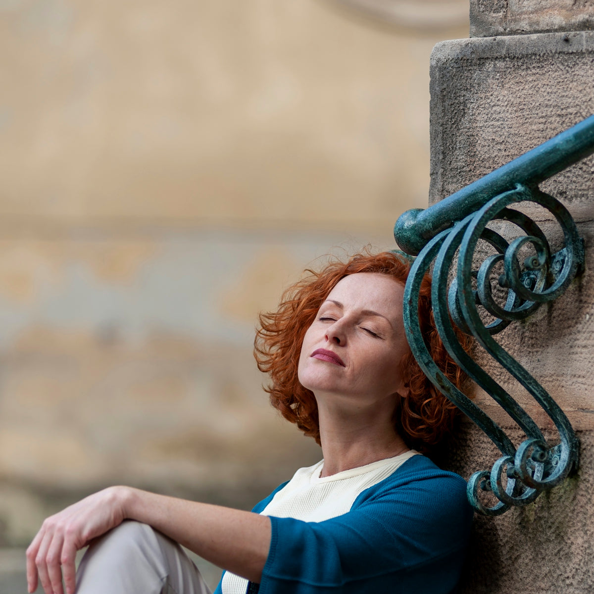 a woman leaning against a wall with her eyes closed